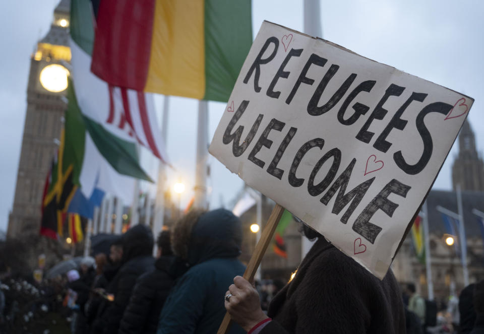 A protester standing near Big Ben holds a sign reading: Refugees welcome.