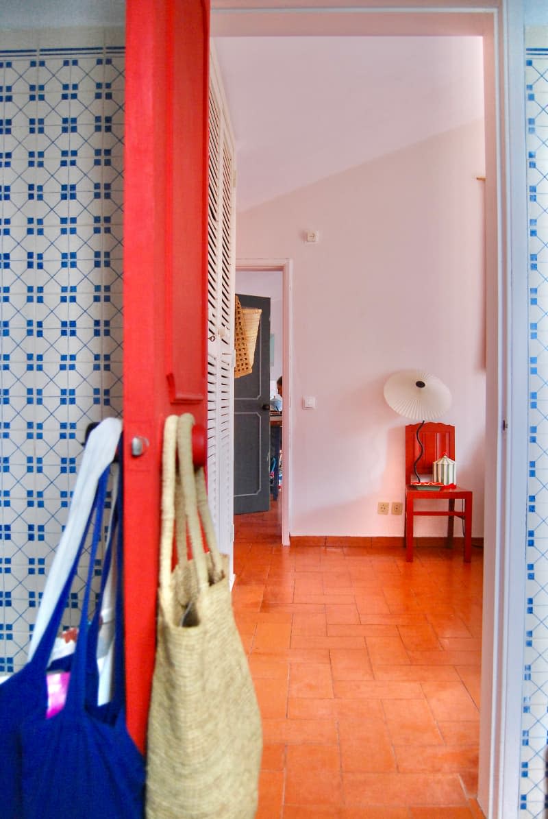 View of chair in white bedroom from red door.