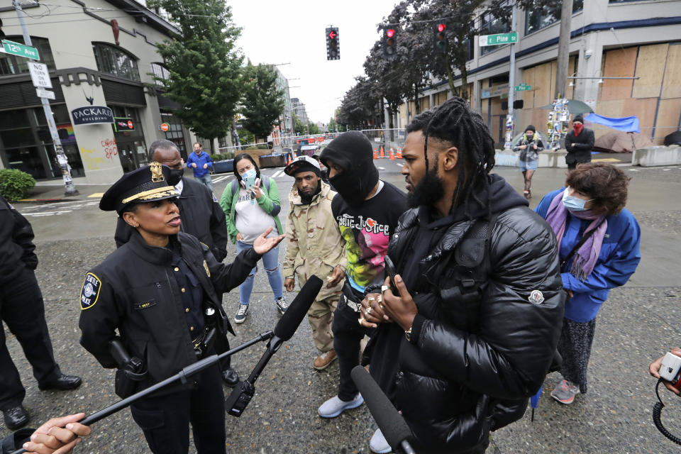 Seattle Police Chief Carmen Best, left, talks with activist Raz Simone, right front, and others near a plywood-covered and closed Seattle police precinct behind them Tuesday, June 9, 2020, in Seattle, following protests over the death of George Floyd, a black man who was in police custody in Minneapolis. Under pressure from city councilors, protesters and dozens of other elected leaders who have demanded that officers dial back their tactics, the police department on Monday removed barricades near its East Precinct building in the Capitol Hill neighborhood, where protesters and riot squads had faced off nightly. Protesters were allowed to march and demonstrate in front of the building, and the night remained peaceful. (AP Photo/Elaine Thompson)