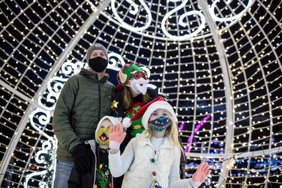 Kevin Schabel, his wife Tami and children Evelyn, 8Tommy, 6, all of Romeo pose for a photo with their grandchildren inside of a light installation in a shape of a giant ornament during Wild Lights at the Detroit Zoo in Royal Oak on Dec. 3, 2020.