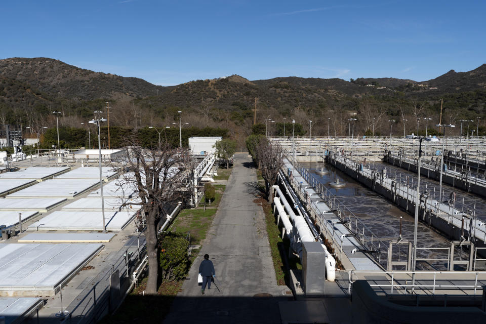 CORRECTS SPELLING TO AGOURA HILLS NOT AGORA HILLS A worker walks past aeration tanks at the Las Virgenes Municipal Water District's Tapia Water Reclamation Facility in Agoura Hills, Calif., Wednesday, Jan. 5, 2022. The wealthy enclave along the Santa Monica Mountains that is haven for celebrities has taken aggressive steps to try to limit water use during California's drought, including lowering the thresholds for fines for those who go over their "water budgets" and threatening to add restrictors to pipes that limit water flow to customers who repeatedly fail to conserve. (AP Photo/Jae C. Hong)