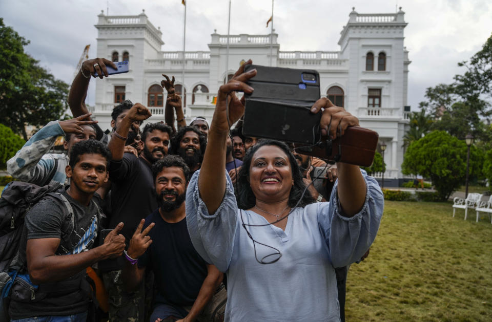 Protesters take a photograph as they leave prime minister Ranil Wickremesinghe's office building in Colombo, Sri Lanka, Thursday, July 14, 2022. Sri Lankan protesters began to retreat from government buildings they seized and military troops reinforced security at the Parliament on Thursday, establishing a tenuous calm in a country in both economic meltdown and political limbo.(AP Photo/Rafiq Maqbool)