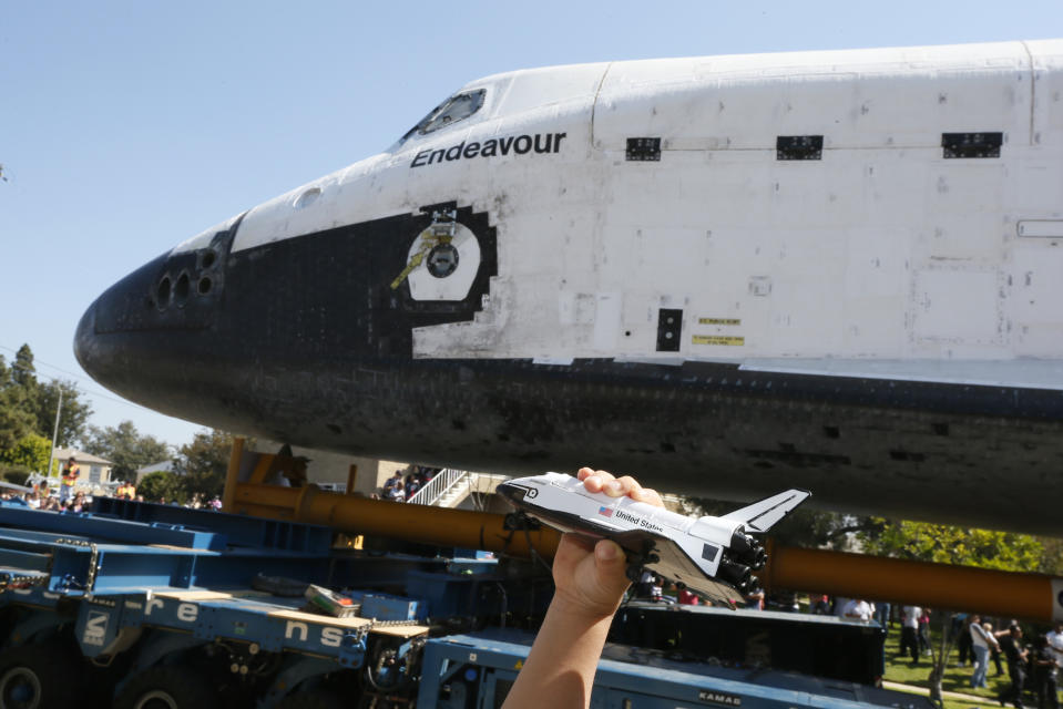 A boy holds a model of the space shuttle Endeavour near the shuttle as it is moved to the California Science Center in Los Angeles on Saturday, Oct. 13, 2012. (AP Photo/Lucy Nicholson, Pool)