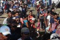 Honduran migrants stand in line for breakfast at a temporary shelter in Tecun Uman, Guatemala in the border with Mexico, Sunday, Jan. 19, 2020. Mexican authorities have closed a border entry point in southern Mexico after thousands of Central American migrants tried to push across a bridge between Mexico and Guatemala. (AP Photo/Moises Castillo)