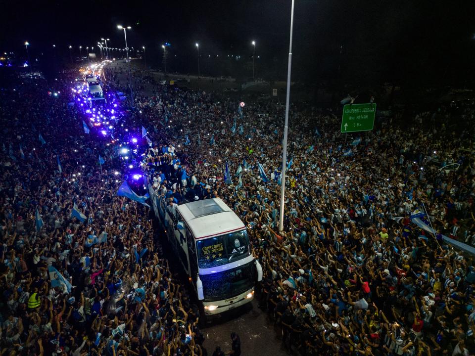 This aerial image taken on December 20, 2022 shows Argentina's players celebrating on board a bus with supporters after winning the Qatar 2022 World Cup tournament as they leave Ezeiza International Airport en route to the Argentine Football Association (AFA) training centre in Ezeiza, Buenos Aires province, Argentina. (Photo by Tomas CUESTA / AFP) (Photo by TOMAS CUESTA/AFP via Getty Images)