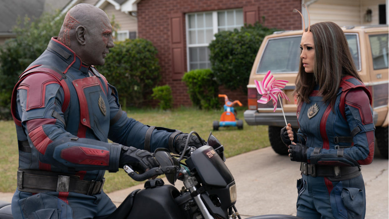  Dave Bautista sits on a bike while talking with Pom Klementieff in Guardians of the Galaxy Vol 3. 