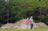 Elaine Nichols, left, is helped by her son David as they walk through Rose Hill United Methodist Church's outdoor Stations of the Cross on Friday, April 10, 2020, in Tomball, Texas. Similar to the Stations of the Cross displayed on stained-glass windows inside churches, this outdoor experience offers scripture and interactive reflections. (AP Photo/David J. Phillip)