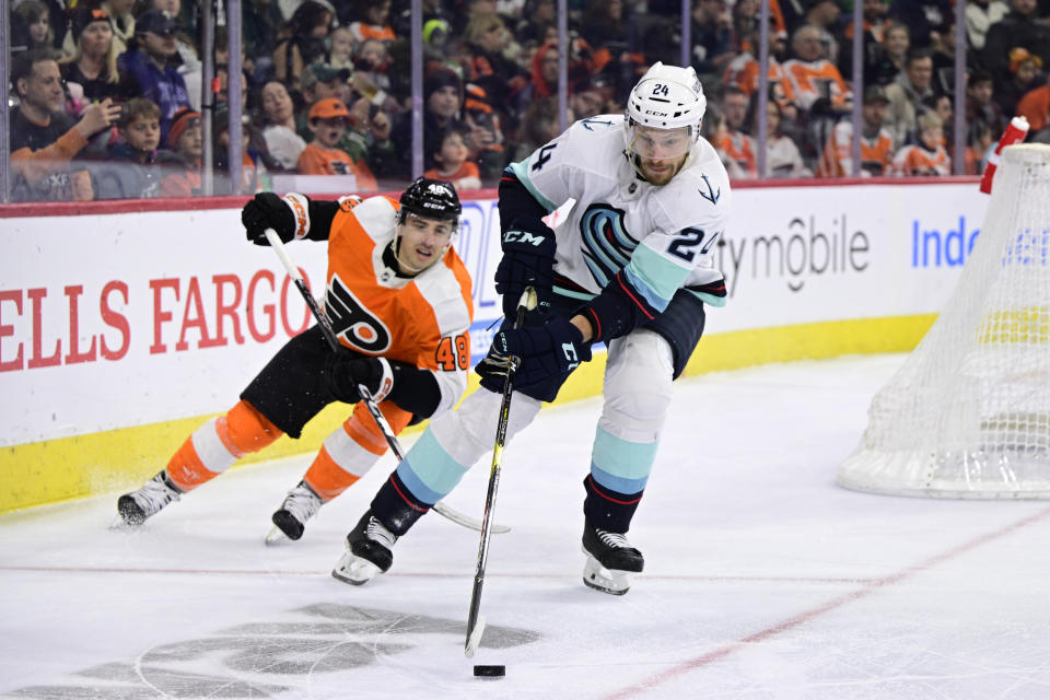 Seattle Kraken's Jamie Oleksiak, right, skates the puck past Philadelphia Flyers' Morgan Frost during the second period an NHL hockey game, Sunday, Feb. 12, 2023, in Philadelphia. (AP Photo/Derik Hamilton)