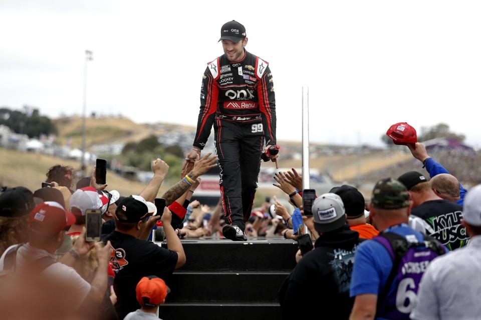 Daniel Suarez walks across a stage greeting fans during driver introductions.