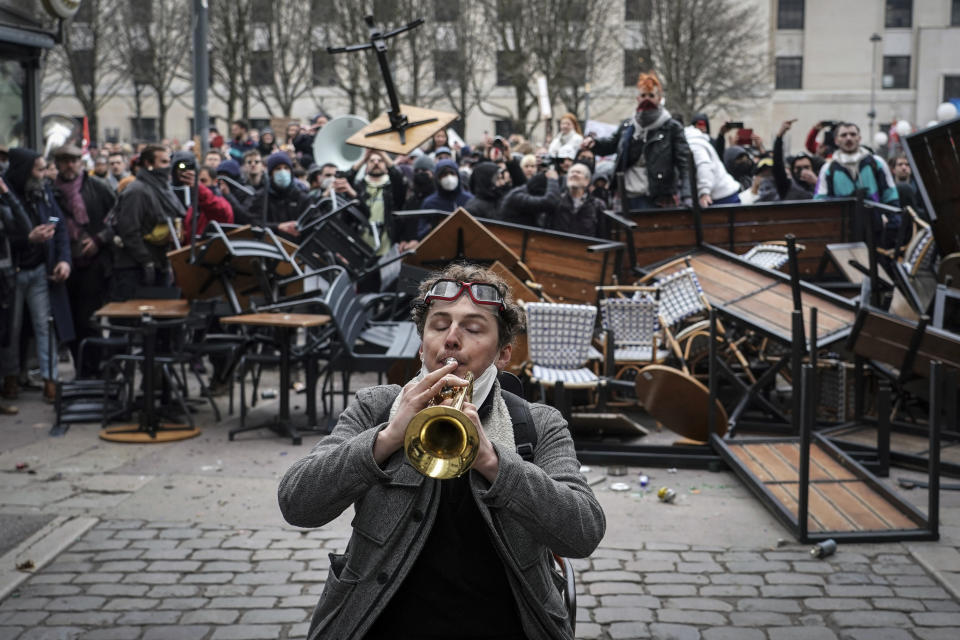 A man plays the trumpet in front of a barricade during a demonstration in Lyon, central France, Tuesday, March 7, 2023. Demonstrators were marching across France on Tuesday in a new round of protests and strikes against the government's plan to raise the retirement age to 64, in what unions hope to be their biggest show of force against the proposal. (AP Photo/Laurent Cipriani)