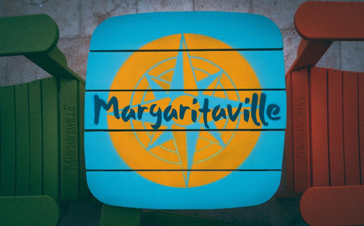 Margaritaville cruises are relatively new experiences for travelers. Explore the options for lovers of the Margaritaville brand. pictured: a turquoise table with Margaritaville spelled out on it in bold