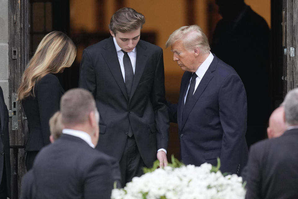 Former President Donald Trump, right, stands with his son Barron, center, and wife Melania, as the coffin carrying the remains of Amalija Knavs, the former first lady's mother, is carried into the Church of Bethesda-by-the-Sea for her funeral, in Palm Beach, Fla., Thursday, Jan. 18, 2024. (AP Photo/Rebecca Blackwell)