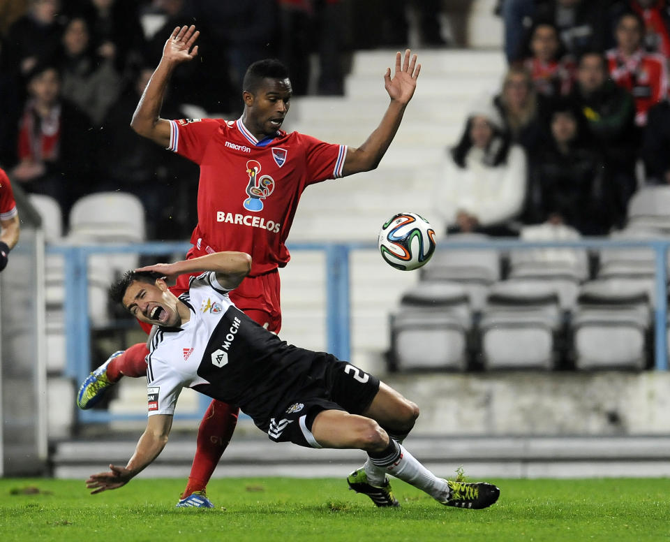 Benfica's is Nico Gaitan, foreground, from Argentina falls on the penalty box after a tackle by Gil Vicente's Armindo 'Brito' Furtado, from Cape Verde, in a Portuguese League soccer match at the Cidade de Barcelos stadium, in Barcelos, northern Portugal, Saturday, Feb. 1, 2014. (AP Photo/Paulo Duarte)