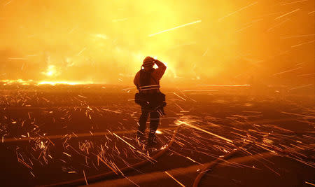 Fire photographer Tod Sudmeier gets hit with flying embers from strong winds at the Solimar brush fire that started early Saturday morning in Ventura County, California December 26, 2015. REUTERS/Gene Blevins