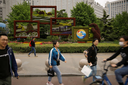 People walk past a flower arrangement set up to mark the upcoming Belt and Road Forum in Beijing, China April 19, 2019. Picture taken April 19, 2019. REUTERS/Thomas Peter