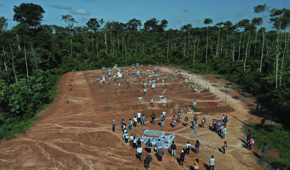 Relatives of people who died from COVID-19 gather next to a clandestine mass grave on the outskirts of Iquitos, Peru, Saturday, March 20, 2021. Local authorities approved the mass burials but never told the families, who believed their loved ones were interred in the nearby local cemetery — and only months later discovered the truth. (AP Photo/Rodrigo Abd)