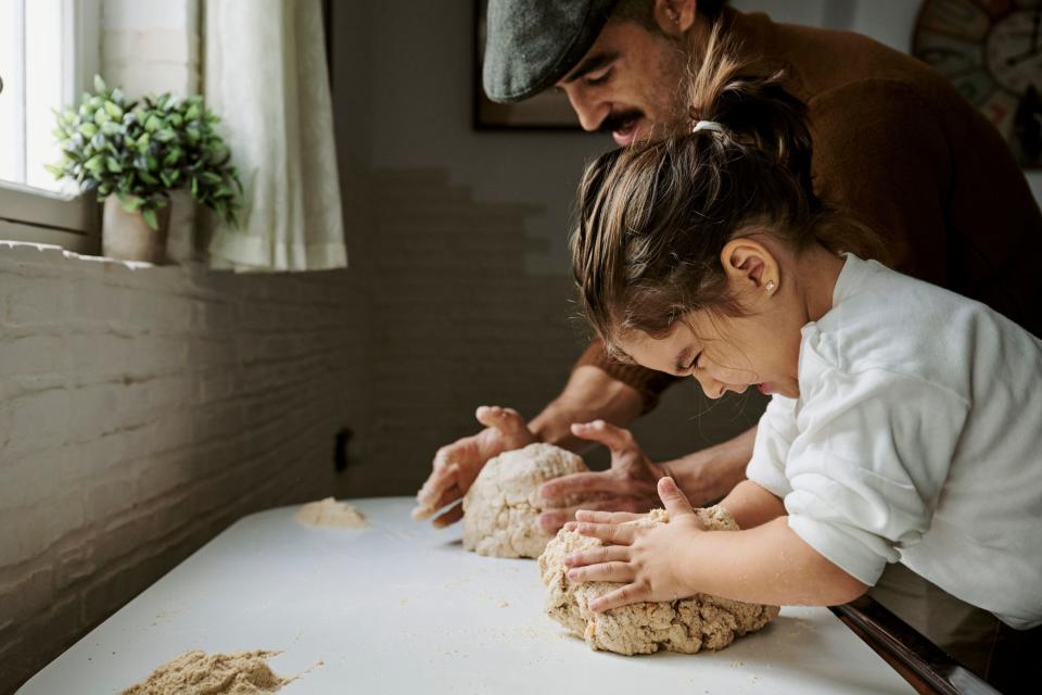 Close up of man and child kneading dough together