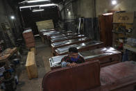 Peruvian migrant coffin maker Cesar Ambrosio finishes the details on a production line of coffins at the Bergut Funeral Services in Santiago, Chile, Thursday, June 18, 2020. The coffin production has had to increase up to 120%, according to Nicolas Bergerie, owner of the factory. His more basic coffin model is called the COVID model and is made to cope with the increase of deaths during the coronavirus pandemic. (AP Photo/Esteban Felix)