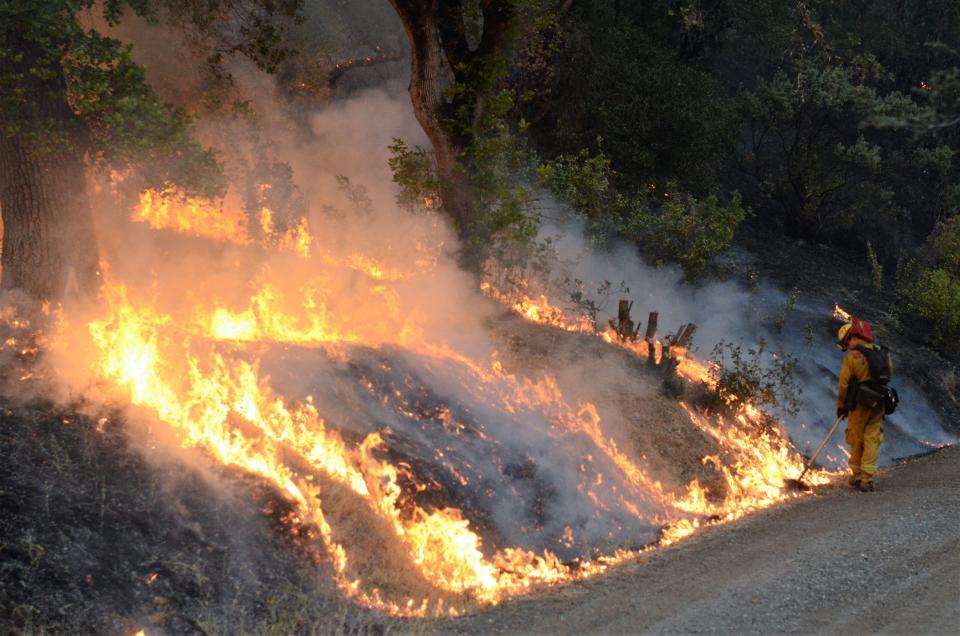 A Cal Fire Butte County Strike Team 9211C firefighter spreads burning brush to burn away excess fuel along Zogg Mine Road near Igo, Calif. The Carr wildfire in Northern California on Sunday has claimed at least five lives, burned hundreds of homes and driven more than 30,000 residents from communities threatened by the relentless blaze.  The fire remained only 5 percent contained early Sunday despite "aggressive" efforts to control the blaze, according to the California Department of Forestry and Fire Protection. 