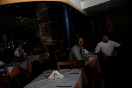 Workers wait for clients at a restaurant during a blackout in Caracas, Venezuela March 25, 2019. REUTERS/Carlos Garcia Rawlins