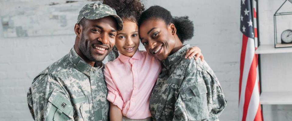 African american female and male soldiers embracing their daughter