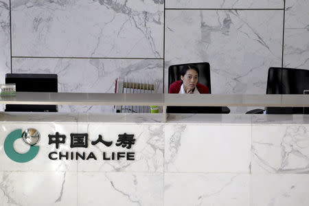 FILE PHOTO: An employee sits at the reception of the headquarters building of China Life insurance in Beijing, China, March 24, 2016. REUTERS/Jason Lee/File Photo