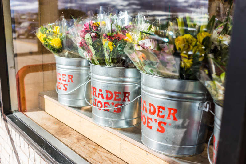 Buckets of flowers with Trader Joe's signs viewed from outside of store