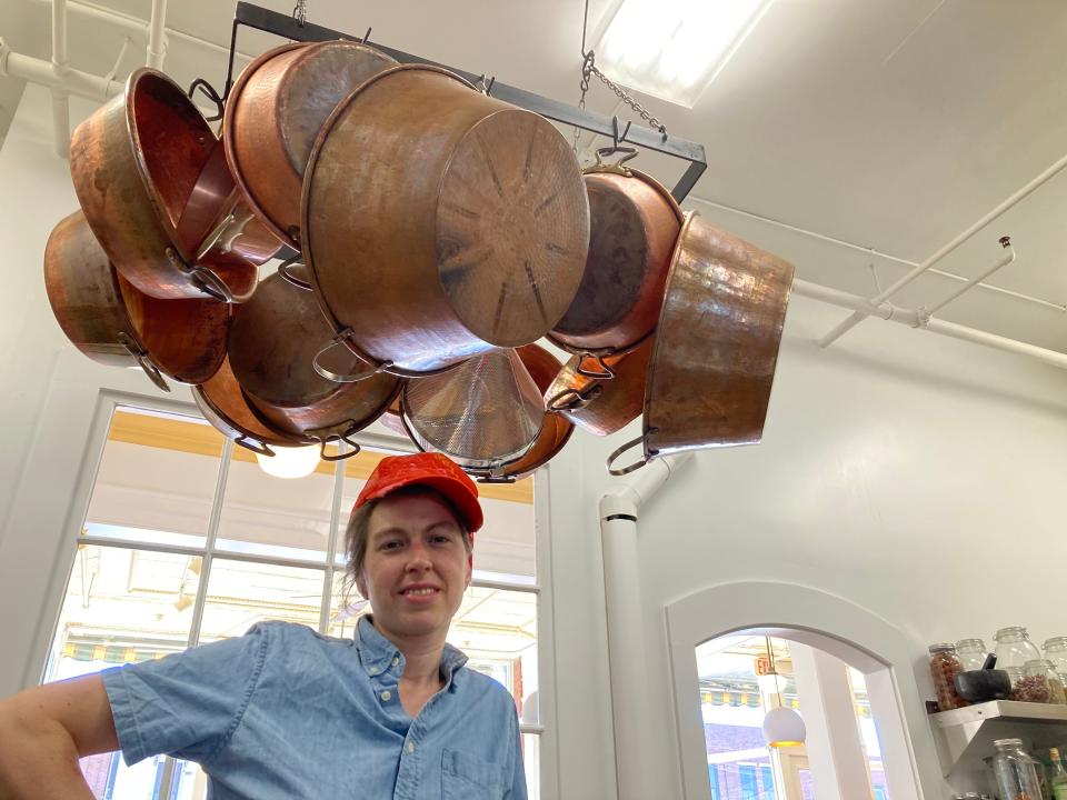 V Smiley, founder of the Minifactory cafe/grocery/food-manufacturing business in Bristol, stands May 9, 2022 beneath pots she uses to make preserves.