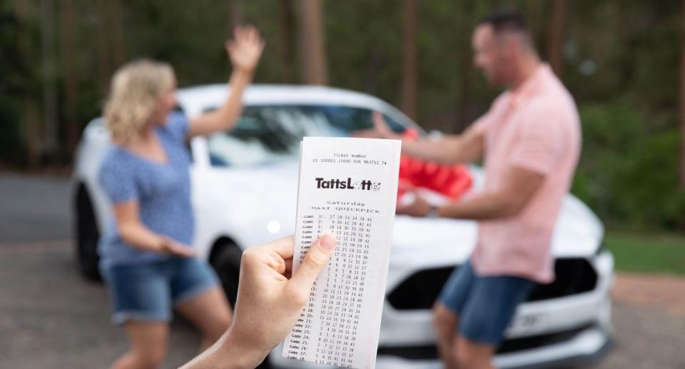 Couple celebrate TattsLotto win in front of brand new car.