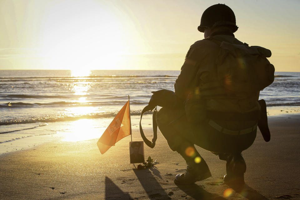 A World War II reenactor pays tribute to a soldier on Omaha Beach in Saint-Laurent-sur-Mer, Normandy, Sunday, June 6, 2021, the day of 77th anniversary of the assault that helped bring an end to World War II. While France is planning to open up to vaccinated visitors starting next week, that comes too late for the D-Day anniversary. So for the second year in a row, most public commemoration events have been cancelled. (AP Photo/David Vincent)