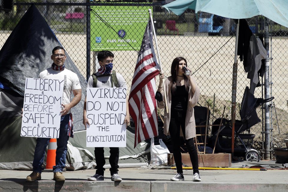 A protester holds a sign during a rally calling for an end to California Gov. Gavin Newsom's stay-at-home orders amid the COVID-19 pandemic, Wednesday, April 22, 2020, outside City Hall in downtown Los Angeles. (AP Photo/Marcio Jose Sanchez)