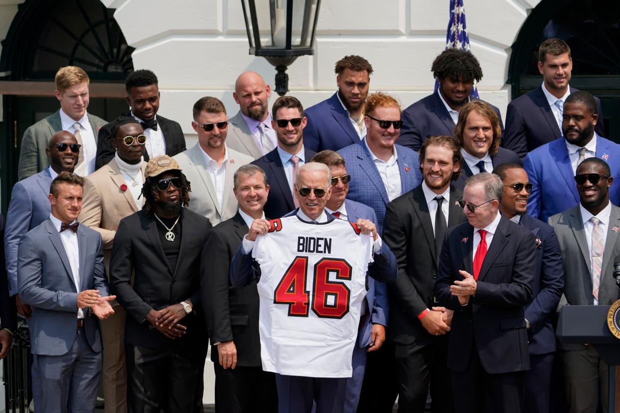 President Joe Biden, surrounded by members of the Tampa Bay Buccaneers, poses for a photo holding a jersey during a ceremony on the South Lawn of the White House, in Washington on Tuesday, July 20, 2021, where Biden honored the Super Bowl Champion Tampa Bay Buccaneers for their Super Bowl LV victory.