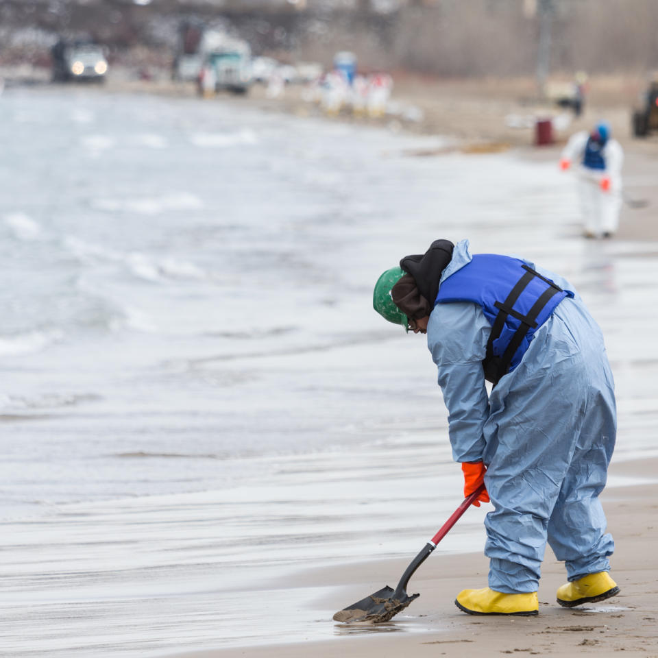 In this March 25, 2014 photo, a worker collects soil from the beach in Whiting, Ind. Crews for oil giant BP worked Tuesday to clean up an undetermined amount of crude oil that spilled into Lake Michigan and affected about a half-mile section of shoreline near Chicago following a malfunction at BP's northwestern Indiana refinery, officials said. (AP Photo/Sun-Times Media, Jim Karczewski) MANDATORY CREDIT, MAGS OUT, NO SALES