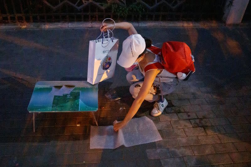 Street vendor Yan Ying packs up her stall after officials ordered her to leave following an outbreak of the coronavirus disease (COVID-19) in Beijing