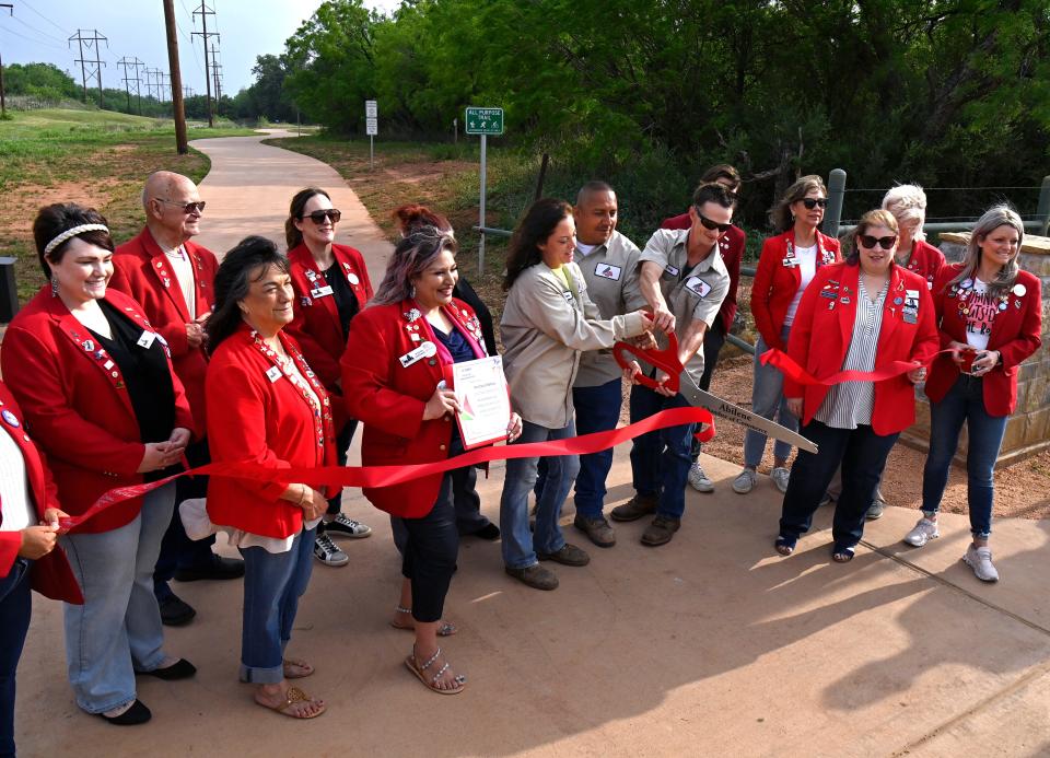 City of Abilene Parks & Recreation Department employees cut the ribbon as the Abilene Redcoats dedicate the Cedar Creek Waterway trail April 27.