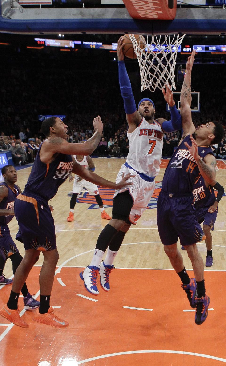 New York Knicks' Carmelo Anthony (7) drives past Phoenix Suns' Gerald Green (14) and Channing Frye (8) during the first half of an NBA basketball game, Monday, Jan. 13, 2014, in New York. (AP Photo/Frank Franklin II)