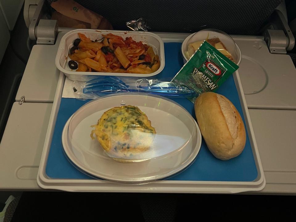 My dinner with pasta, yellow egg muffin, bread, and pastry on a blue tray.