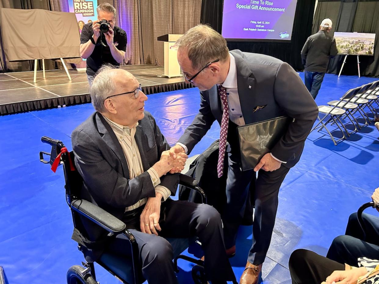 Joseph Ramai, sitting, shakes hands with Saskatchewan Polytechnic president and CEO Larry Rosia Friday. The Joseph Alfred Remai Family Foundation donated $25 million to the campaign raising money for Saskatchewan Polytechnic's new campus.  (Trevor Bothorel/ CBC News - image credit)