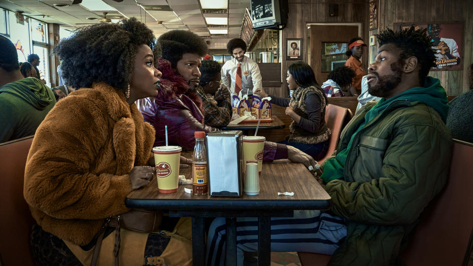 Yo-Yo, Slick Charles, and Fontaine chat as they sit in a fried chicken restaurant in They Cloned Tyrone