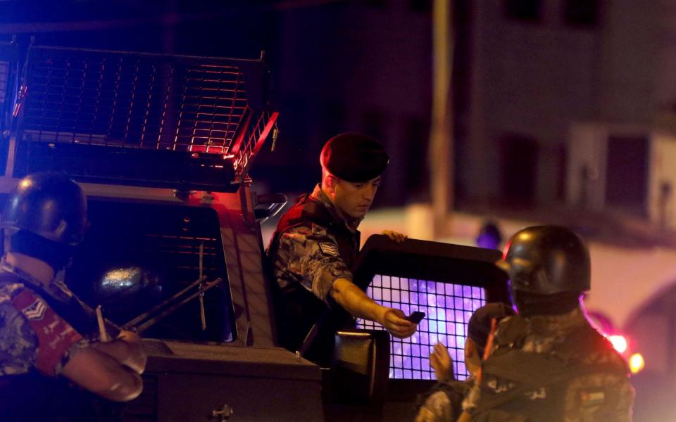 Security forces members speak as they stand guard outside the Israeli embassy in the residential Rabiyeh neighbourhood of the Jordanian capital Amman following an 'incident' - Credit: AFP