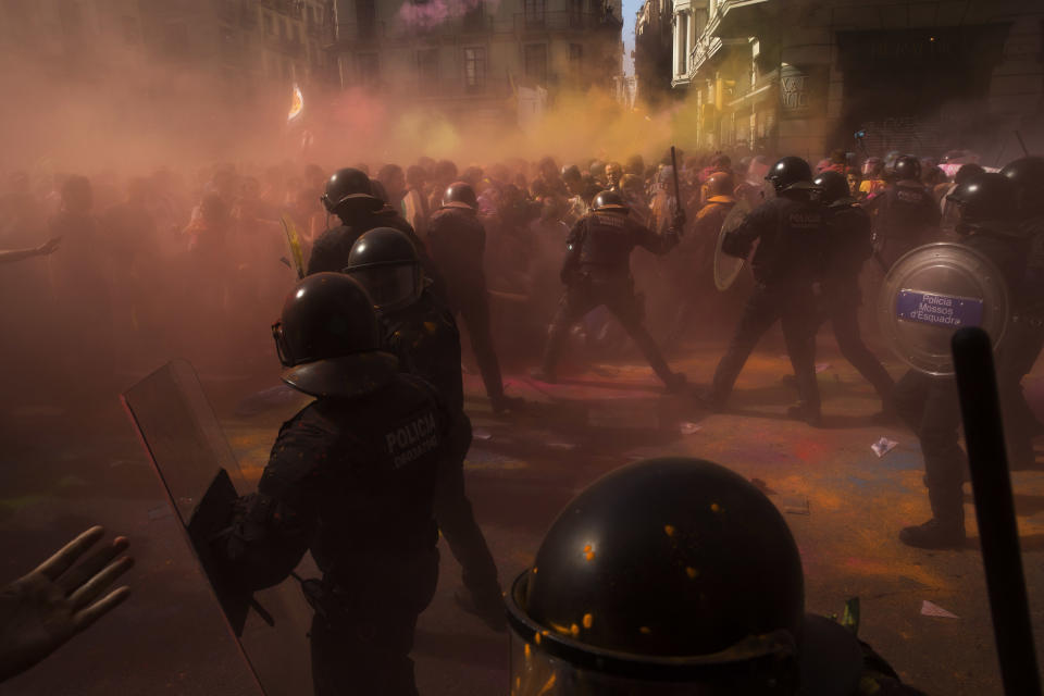 Catalan police officers clash with pro independence demonstrators on their way to meet demonstrations by member and supporters of National Police and Guardia Civil, as colored powder is seen in the air after being thrown by protesters, in Barcelona on Saturday, Sept. 29, 2018. (AP Photo/Emilio Morenatti)