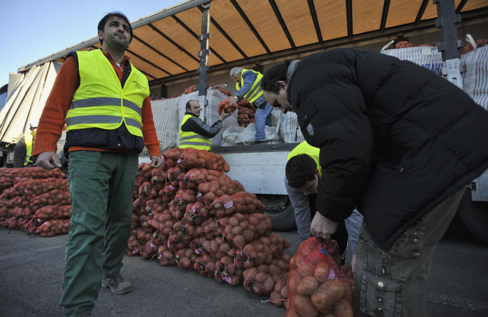 Farmers unloads sacks of potatoes from a truck for sale at cost price in the northern Greek town of Katerini, Greece on Saturday, Feb. 25 2012. Farmers in northern Greece have joined forces with local residents to provide cheap produce to people whose family budgets have been slashed by the financial crisis, and also to help producers who say they are being squeezed by middlemen. Hundreds of families turned up Saturday in this northern Greek town to buy potatoes at massively reduced prices, sold directly by producers at cost price. (AP Photo/Nicolas Giakoumidis)