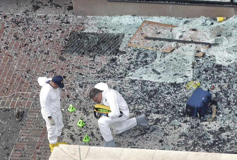 This photo by Associated Press photographer Elise Amendola shows men in protective suits putting numbers on debris as they investigate the scene at the Boston Marathon bombing in Boston on Tuesday, April 16, 2013. Amendola, who recently retired from the AP, died Thursday, May 11, 2023, at her home in North Andover, Mass., after a 13-year battle with ovarian cancer. She was 70. (AP Photo/Elise Amendola, File)