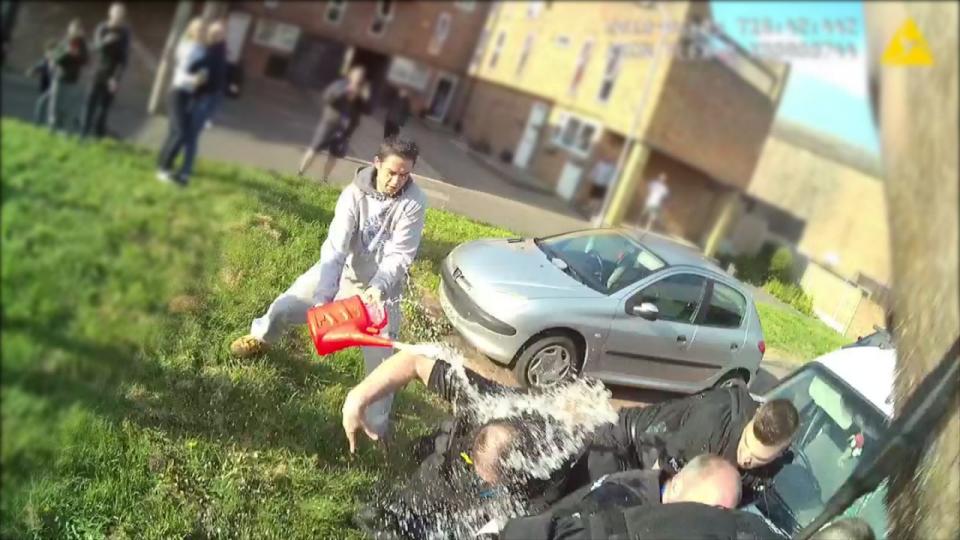 The moment police officers were doused with petrol in Basildon, Essex, in May last year. (SWNS)