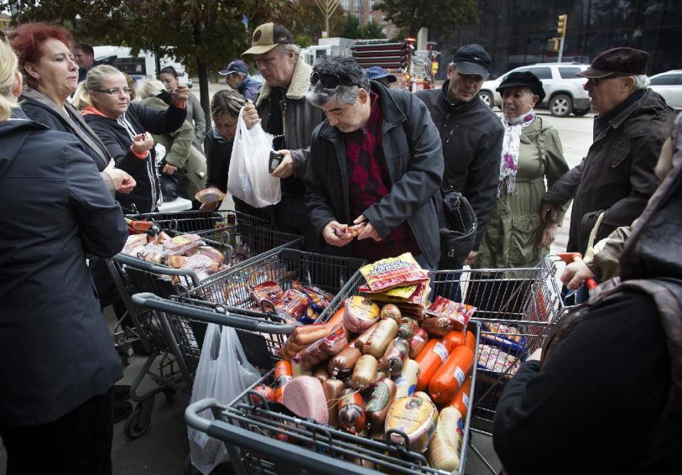 A customer browses food piled into shopping carts on Brighton Beach Avenue, Wednesday, Oct. 31, 2012, in the Brooklyn borough of New York. People in the coastal corridor battered by superstorm Sandy took the first cautious steps Wednesday to reclaim routines upended by the disaster, even as rescuers combed neighborhoods strewn with debris and scarred by floods and fire. (AP Photo/ John Minchillo)