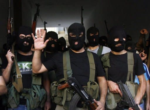 Lebanese masked gunmen from the al-Muqdad clan gather for a press conference in Beirut's southern suburbs. Dozens of Syrians were kidnapped and Syrian-owned shops vandalised in Beirut on Wednesday, reports said, while Saudi Arabia and the UAE told their citizens to leave Lebanon in the face of threats