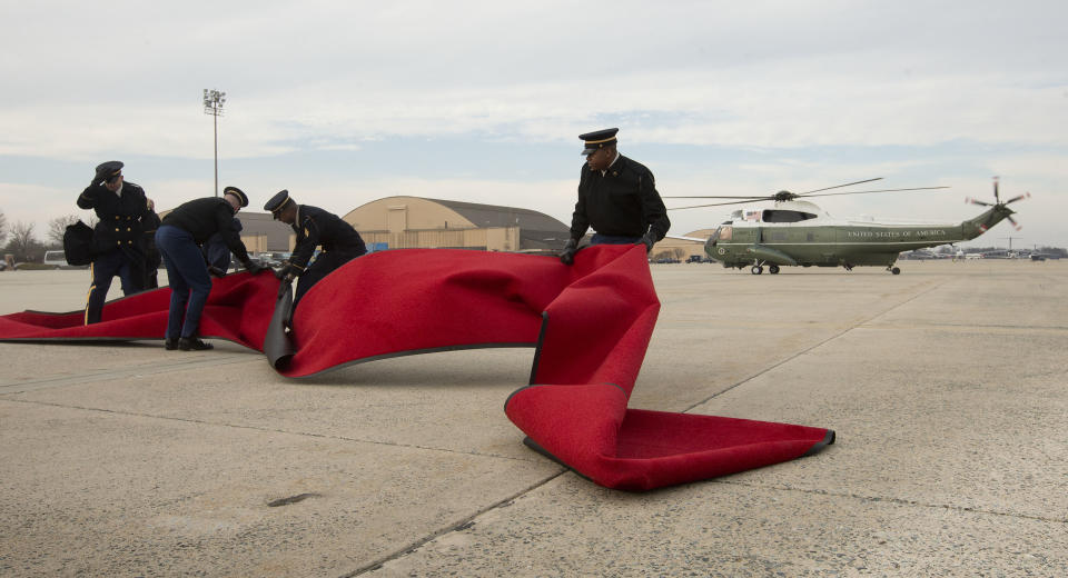 Members of the US Air Force attempt to hold the red carpet before it could blow away from the air gust caused by the arrival of Marine One helicopter, with President Barack Obama aboard, Monday, Feb. 10, 2014, at Andrews Air Force Base, Md. The carpet was placed on the tarmac to be used by Obama and French President Francois Hollande for boarding Air Force One for a trip to Monticello, President Thomas Jefferson's estate in Charlottesville, Va. (AP Photo/Pablo Martinez Monsivais)