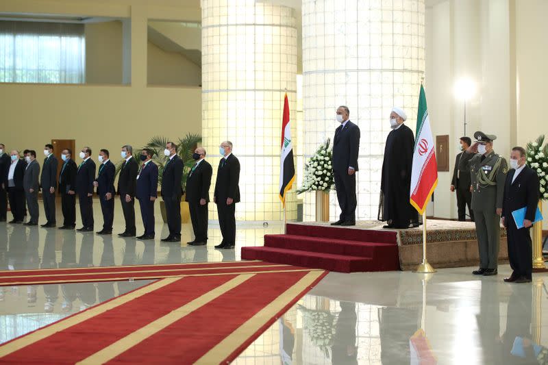 Iranian President Hassan Rouhani welcomes the Iraqi Prime Minister Mustafa al-Kadhimi as they wear protective masks, in Tehran