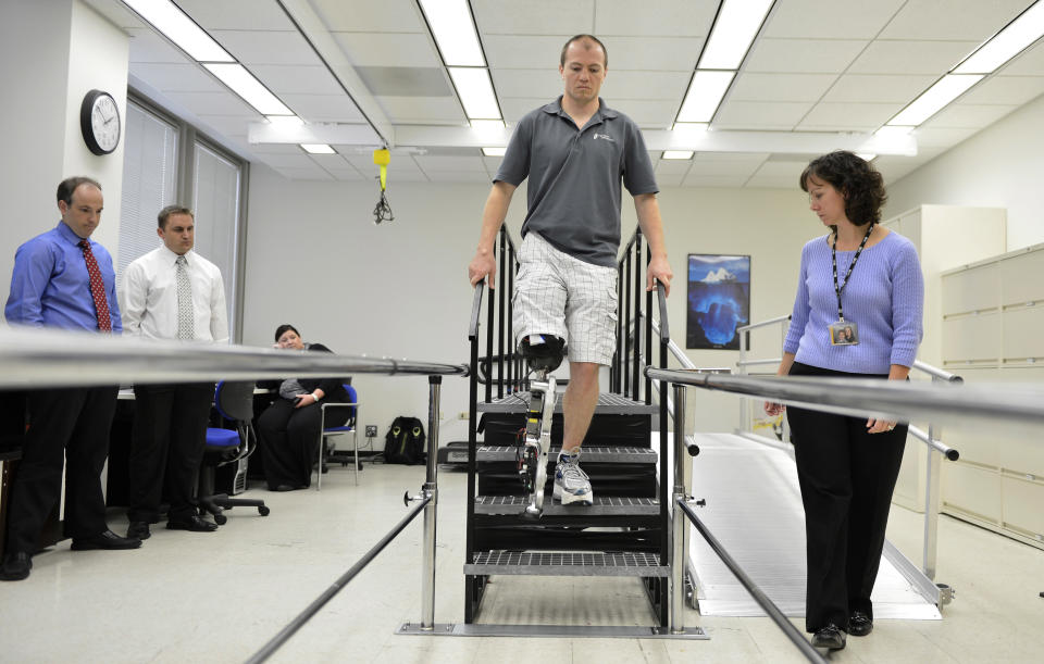 In this Oct. 25, 2012 photo, physical therapist assistant Suzanne Finucane, right, helps Zac Vawter as he practices walking with an experimental "bionic" leg at the Rehabilitation Institute of Chicago. After losing his right leg in a motorcycle accident, the 31-year-old software engineer signed up to become a research subject, helping test a trailblazing prosthetic leg that's controlled by his thoughts. He will put this leg to the ultimate test Sunday, Nov. 4 when he attempts to climb 103 flights of stairs to the top of Chicago's Willis Tower, one of the world’s tallest skyscrapers. (AP Photo/Brian Kersey)