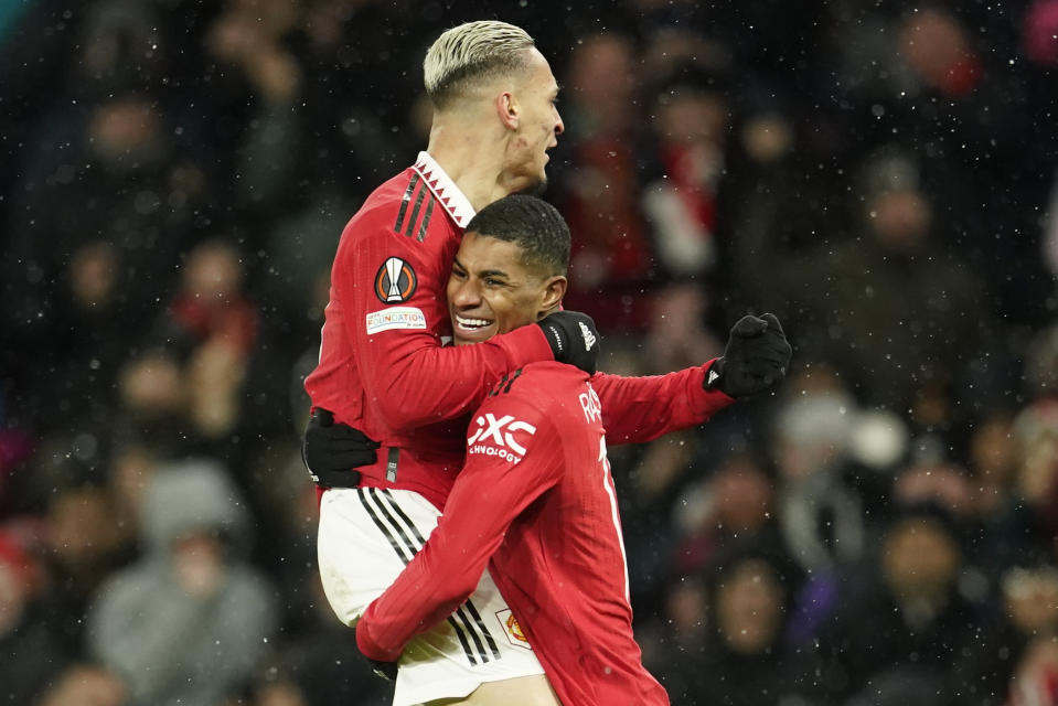 El brasileño Antony (izquierda), abraza a Marcus Rashford, su compañero en el Manchester United, luego de anotar ante Real Betis, en un encuentro de la Liga Europa, el jueves 9 de marzo de 2023 (AP Foto/Dave Thompson)